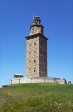 Old lighthouse under a bright blue sky, surrounded by green landscape, Torre de Hércules, Torre de