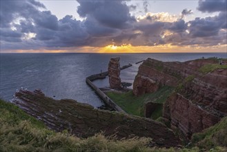 Red sandstone cliff with Lange Anna on the offshore island of Heligoland, pier as protection