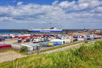 A busy harbour with a large ferry and numerous trucks under a cloudy sky by the sea, Rosslare