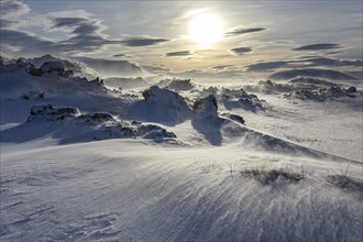 Solidified lava and stones in a snowstorm, windy, sunny, backlight, Myvatn, Iceland, Europe