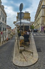 Cosy alleyway café in a cobbled alley under a cloudy sky, Lisbon, Portugal, Europe