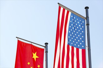 Various national flags fly on flagpoles against a blue sky, Chinese flag, American flag