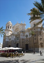 Historic cathedral with surrounding palm trees and café terraces under a clear sky, Catedral de