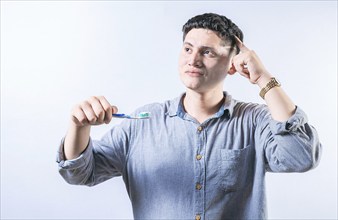 Pensive man holding toothbrush isolated. Thoughtful person holding toothbrush and looking up