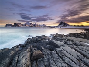 Rocky coast, snow-capped mountains in the background, Vestvågøya, Lofoten, Norway, Europe