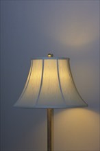 A warmly illuminated bedside lamp with a white shade, cosy