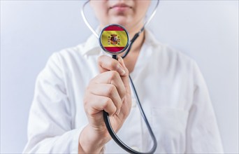 Female doctor holding stethoscope with Spain flag. Spanish Health and Care concept