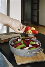 Adding salt or pepper from hand spice mill to vegetables in a frying pan