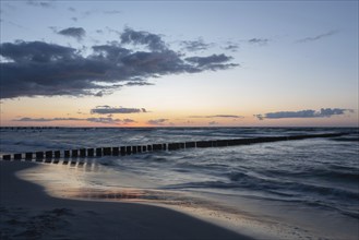 Calm beach with gentle waves and a wide horizon at sunset, breakwater, groynes, Baltic Sea