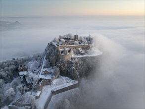 Aerial view of the Hegau volcano Hohentwiel with Germany's largest fortress ruins on a cold, foggy