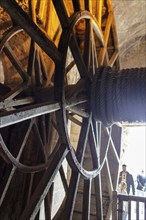 Detail of a wooden wheel with people illuminated in the background, Le Mont-Saint-Michel