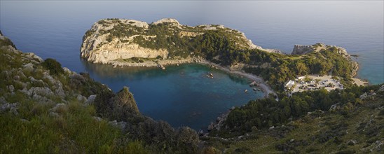 Panoramic view of a rocky bay surrounded by wooded hills and clear, calm waters, Anthony Quinn Bay,