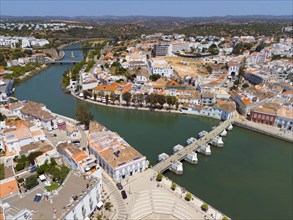 River with bridge through a Mediterranean-style town, recognisable by the red roofs and urban