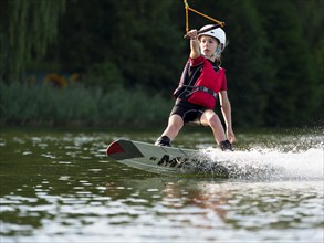 Boy or girl with wakeboard in the lake, water sports, water skiing in the wake park