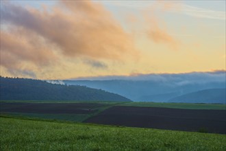 Landscape with fields and mountains in the background, clouds in the sky at sunrise, autumn,