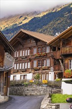 Traditional wooden houses in an alpine village with floral decorations in front of mountains, Lake