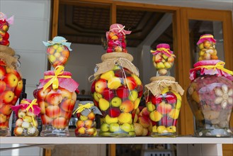 Colourful jars with creatively pickled fruit as decorative arrangements in front of a rustic