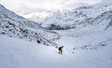 Skiers skiing downhill in a snow-covered mountain landscape in the Madritschtal valley, Ortler