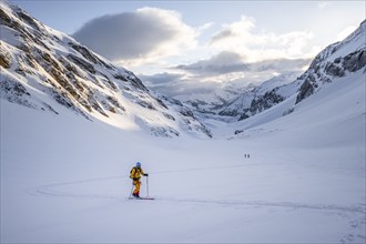 Ski tourers in a snowy mountain landscape in the morning light, view into the Iffigtal, cloudy