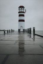 Lighthouse on a wooden jetty, surrounded by a rainy sky, Podersdorf, Burgenland, Austria, Europe