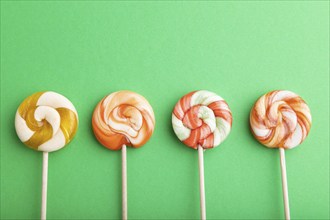 Four lollipop candies on green pastel background. copy space, top view, flat lay