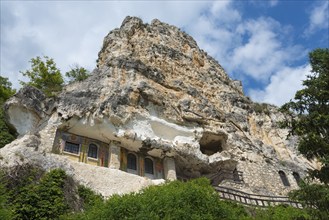 Historic cave church built into a steep rock under a clear blue sky, Bulgarian Orthodox cave