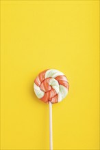 Single lollipop candy on yellow pastel background. copy space, top view, flat lay