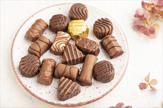 Chocolate candies with cup of coffee and hydrangea flowers on a white concrete background. side