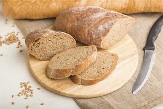 Sliced bread with different kinds of fresh baked bread on a white wooden background. side view,