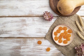 Jelly pumpkin candies on white wooden background and linen textile. copy space, top view, flat lay.