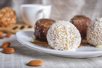 Energy balls cakes with chocolate caramel and coconut on white plate on linen napkin, selective