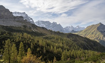 Mountain panorama with steep rocky peaks, yellow-coloured larches in autumn, hike to the summit of