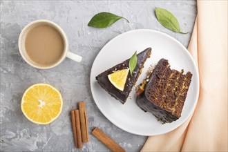 Homemade chocolate cake with orange and cinnamon with cup of coffee on a gray concrete background