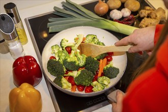 Vegan cooking: Close-up of a pan with broccoli, carrots and cocktail tomatoes