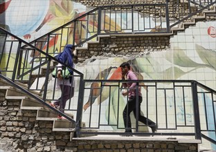 Passers-by walk up a staircase painted with roses in Tehran. The city of Tehran is changing the