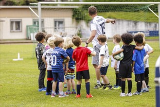 Volunteer coach trains children on the football pitch, Bonn, 19.06.2024