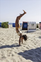 Young woman doing a handstand on the North Sea island of Borkum, 18/05/2024