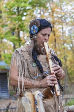 Woman dressed as Native American Indian plays hand made wooden flute at Billie Creek Village in