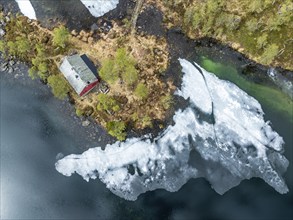 Typical norwegian red house, melting ice on a lake, Gaularfjell mountains, aerial view, along