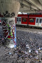 Empty spray paint cans, on a railway line below a road bridge, thrown away, disposed of by the