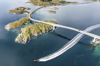 Aerial view of bridge connecting islands at the norwegian coast, motor boat passing below the