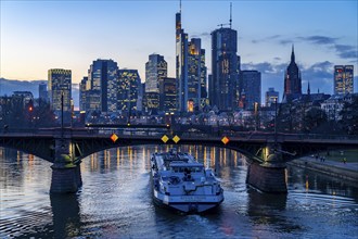 Skyline of the city centre of Frankfurt am Main, river Main, dusk, Ignatz-Bubis-Bridge, cargo ship,