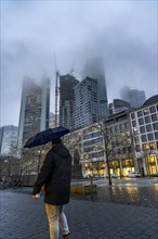 Rainy weather, freezing rain, Goetheplatz, high-rise skyline in clouds, passers-by hurrying through