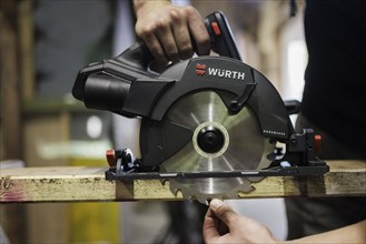 A man adjusts the cutting depth of a hand-held circular saw. Berlin, 14.08.2024