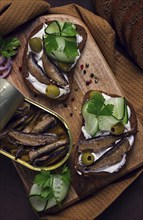 Sandwiches, black bread with sprats, cream cheese, cucumbers, on a cutting board, top view,