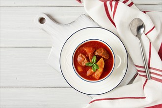 Potatoes stewed with meat, in tomato sauce, with spices and herbs, no people, on a white table