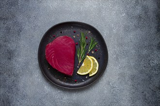 Fresh red tuna fillet, for steak, raw, top view, on a black plate, no people