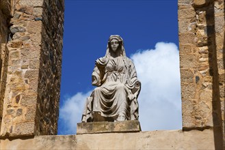 Stone figure of a historical figure in a stone frame in front of a clear blue sky, Teatro Romano de