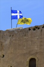 Top left flag of Crete behind it flag with symbol of Eastern Orthodox Greek Orthodox Church yellow