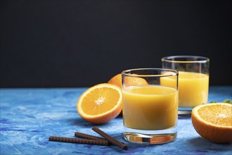 Glass of orange juice on a black and blue background. Hard light, contrast. Side view, copy space